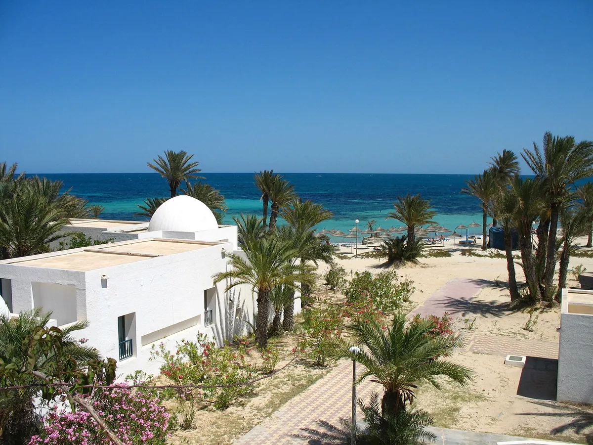Edifici bianchi con la cupola tra le palme, davanti al mare turchese di Djerba