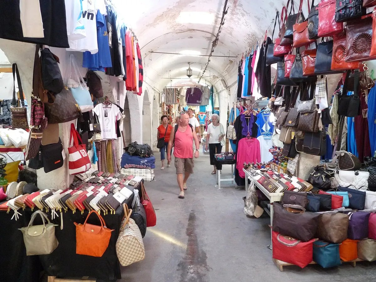 Un vicolo coperto del souk di Houmt Souk con borse, vestiti e tessuti appesi ai lati