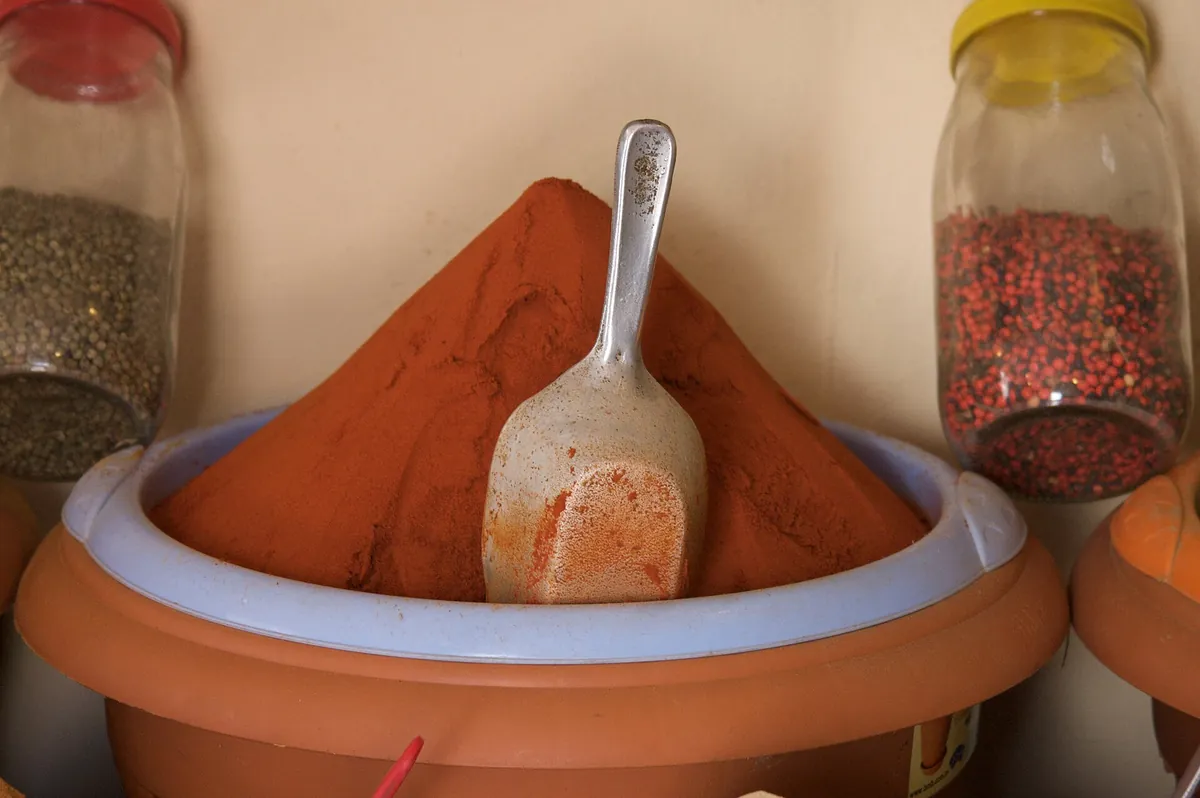 Un mucchio di paprika rossa con una paletta, tra barattoli di spezie, nel souk di Houmt Souk