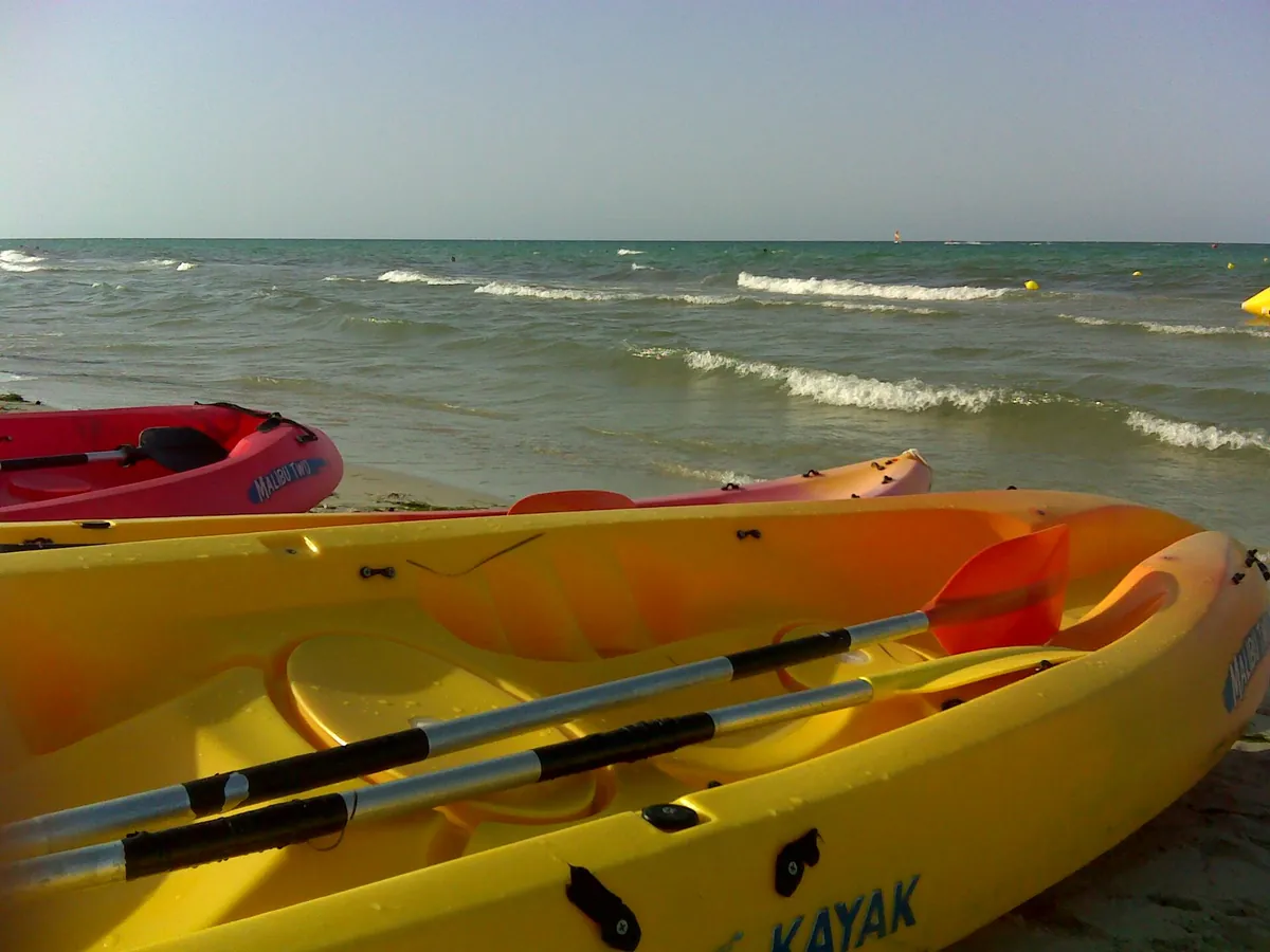 Kayak colorati sulla sabbia davanti al mare mosso, nella zona di Midoun